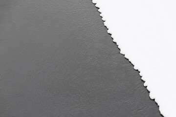 Wall Mural - diagonal section of flat white snow at edge of dark river water