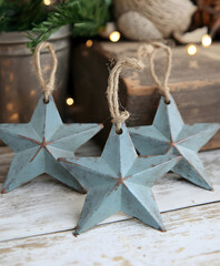 Aufkleber - Three rustic blue metal star decorations hang from twine, set against a wooden backdrop and softly lit ambiance, perfect for festive decor