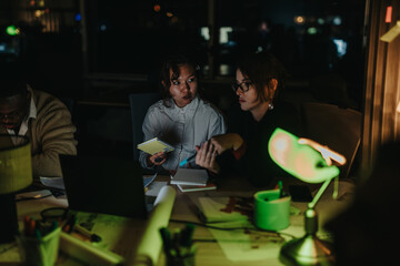 Sticker - A diverse group of colleagues collaborates intensely around a desk in a dimly lit office. They are engaged in brainstorming sessions and analyzing project details, aiming to meet an upcoming deadline.