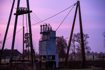 Electric transformer, pylons and wires on colorful evening sky