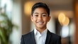 © Chimera - handsome portrait of a male kid wearing an exquisite black suit and white shirt, with a confident smile with a light blurred office lobby background
