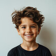 © wetzkaz - curly-haired smiling boy in black t-shirt against neutral backdrop