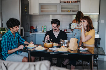 Poster - Three young adults share a relaxed meal at the dining table in a contemporary kitchen setting, enjoying good company and conversation.