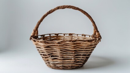 Poster - Woven Rattan Basket with Handle Isolated on a Light Background for Storage and Decoration Purposes
