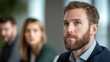 © Priya - Man with beard at meeting looking thoughtful.