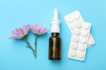 Wall Mural - Allergy treatment. Nasal spray, pills and flowers on light blue background, flat lay