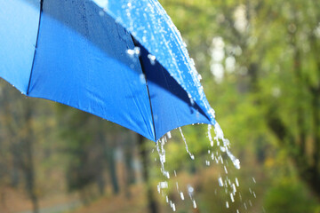 Wall Mural - Open blue umbrella under pouring rain outdoors, closeup