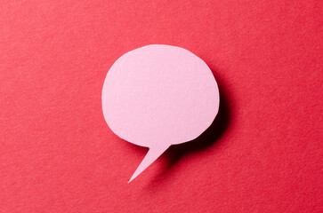 Poster - Pink blank cut out paper speech bubble with shadow and copy space for text on red background, close-up flat lay top view conceptual backdrop