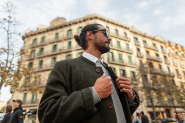 Stylish handsome fashion man in casual city clothes with coat walking in Barcelona city