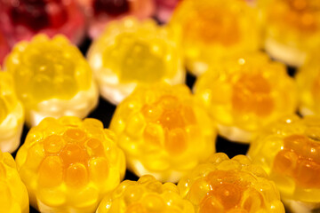 Wall Mural - Red and yellow gummy candies resembling raspberries and pineapples are arranged on a black background. The candies have a shiny, translucent texture.
