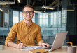 © Sachin - Young man working. Man with laptop, writing. Happy man at desk in office for business planning. Person working with notebook and computer for startup business success.