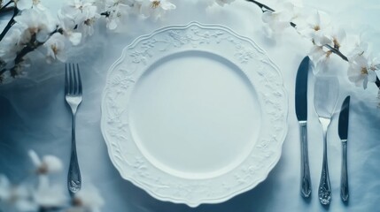 Poster - Elegant table setting with white plate and silver cutlery surrounded by delicate cherry blossoms on a soft blue background. Generative AI