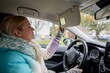© fotodrobik - A Young Woman is Adjusting the Sun Visor in her Car while Enjoying the Daylight Hours