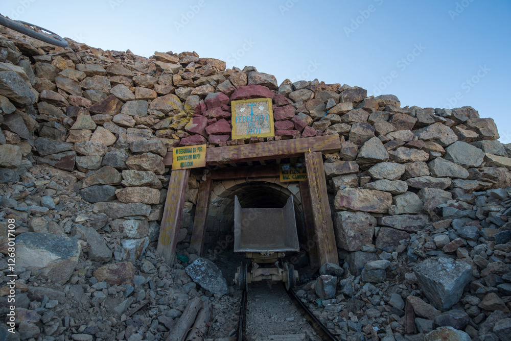 Old train tracks with a mining cart in the entrance leading into a mine ...