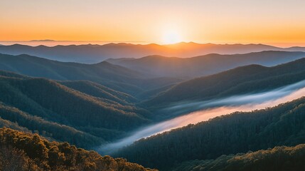 Wall Mural - Majestic sunset over rolling mountains and valleys, with mist flowing through the landscape.