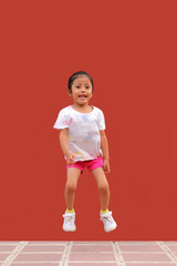 Wall Mural - 3-year-old Latina brunette girl jumps with happiness, plays and has fun in poverty