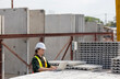 © Ron - Civil engineer in safety suit is using his computer or laptop to check the quality of slabs and precast floorboard in production line. A male engineer with his computer using technology in a factory.