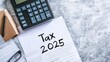 © Thirawat - 'Tax 2025' written on it, tax forms, and a calculator arranged neatly on a desk, depicting the critical tax preparation for the upcoming year.