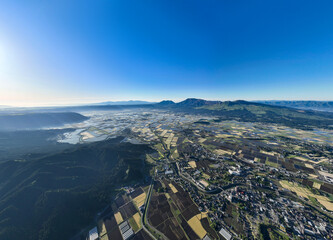 Fototapete - 阿蘇市、農地、農業、阿蘇山、風景、景色、パノラマ、絶景、空撮、ドローン、山麓、都市、街、社会、田畑、農家、道路、インフラ、暮らし、観光、旅行、観光地、青空、地平線、展望、大地、背景、コピースペース、住宅、不動産、環境、自然、景観、明るい、快晴、昼間、超広角、山林、森林、カルデラ、盆地、地形、地理、広告、俯瞰、ハイアングル、行政、自治体、田んぼ
