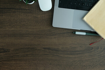 Wall Mural - Wooden desk setup with laptop, notebook, and greenery accents, ideal for business or tech visuals.