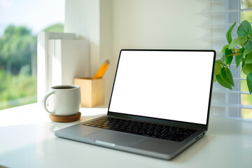 Fototapete - Home office desk featuring a blank-screen laptop, pencils, books, and cozy decor for productivity.