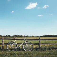 Fototapete - Bicycle resting against rustic fence in a tranquil countryside setting under clear blue sky. Generative AI