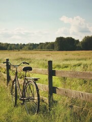 Poster - Bicycle resting against a wooden fence in a peaceful countryside landscape during a sunny afternoon. Generative AI