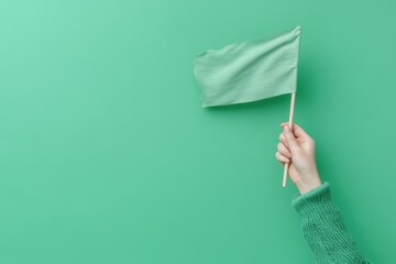 Wall Mural - Hand holding a green flag against a green background