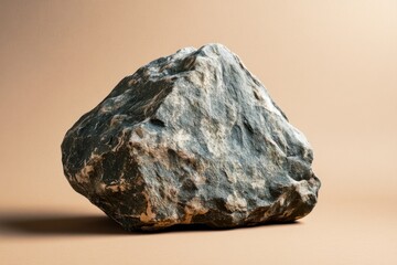 Poster - A single gray rock sits on a tan background