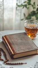 Poster - On a serene white table, a beautifully designed leather-bound book lies open, accompanied by a refreshing glass of amber tea