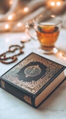 Poster - On a tranquil white surface, a beautifully crafted leather-bound book rests gently next to a cup of amber tea, inviting reflection and peaceful moments. Soft light adds warmth to the setting