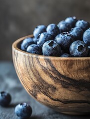 Poster - Rustic wooden bowl filled with fresh blueberries showcasing natural textures and vibrant colors