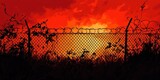 Barbed wire fence stands against a fiery orange sunset