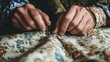 © AlfaSmart - Adult male hand sewing textile with needle on floral fabric close-up