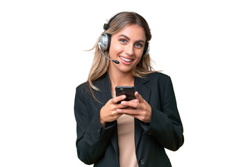 Wall Mural - Telemarketer pretty Uruguayan woman working with a headset over isolated background sending a message with the mobile