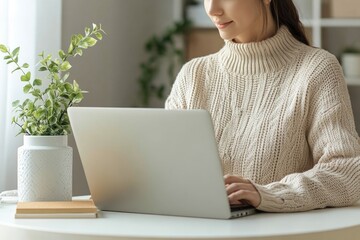 Wall Mural - A woman sits at a table with a laptop and is typing away