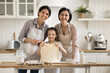 © fizkes - Family cooking tradition. Smiling senior grandma adult mom little daughter posing for portrait at kitchen table look at camera show rolled dough made from natural ingredients for preparing pasta pizza