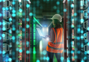 Poster - Woman contractor inside server room. Girl is system administrator. Data center contractor. Server cabinets glow green. Woman with laptop among telecommunications equipment. Engineer maintains servers