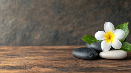 Poster - White flower and black stones arranged on wooden table in a serene spa still life setting