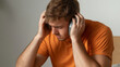 © Panupan - Stressed individual holding his head while wearing headphones, expressing frustration and anxiety. scene captures moment of emotional distress and overwhelming feelings