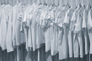 Poster - A collection of white clothing items are hanging on a rack, with each piece neatly folded and arranged in a row. The clothes are all of the same color