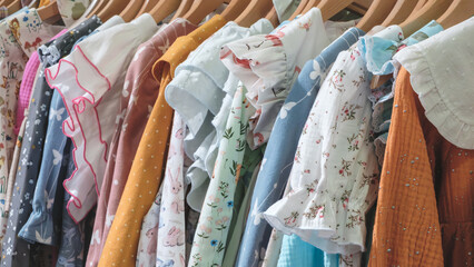Poster - A rack of clothes with a variety of colors and patterns. The clothes are hanging on a rack, and there are many different types of clothing, including shirts, dresses, and jackets