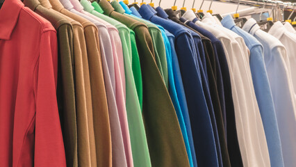 Poster - A row of shirts hanging on a rack, with a variety of colors and styles. Concept of organization and order, as the shirts are neatly hung and arranged in a row
