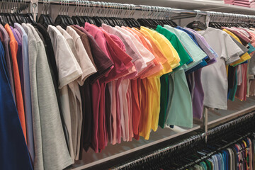 Poster - A rack of colorful shirts in a store. The shirts are arranged in a rainbow order, from light to dark. The display is eye-catching and inviting, drawing the attention of potential customers