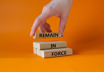 Remain in Force symbol. Concept words Remain in Force on wooden blocks. Businessman hand. Beautiful orange background. Business and Remain in Force concept. Copy space