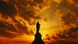 © Kitta Studio - Dramatic Silhouette of Golden Statue Against Colorful Sunset Sky