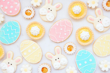 Sticker - Easter or spring themed baking background with assorted cookies and sweet desserts. Top view on a white marble background.