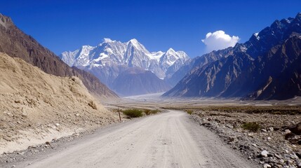 Canvas Print - A dirt road leads toward towering snow capped mountains