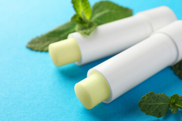 Sticker - Natural lip balms and mint leaves on light blue background, closeup