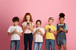 © Prostock-studio - Online education concept. Adorable multinational schoolkids stuck in smartphones on pink background